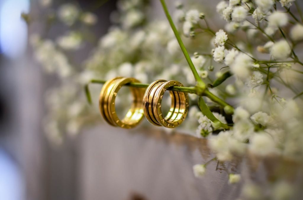 Close-up of shimmering gold wedding bands delicately resting on babys breath flowers, symbolizing love and commitment.